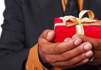 African-American male hands holding a red velvet box with gold ribbon.